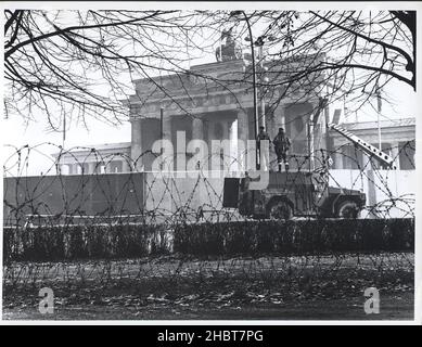 November 1961. In vollem Kampfkleid bewachen ostdeutsche Truppen Arbeiter hinter dem Bildschirm, die die Berliner Mauer verstärken Stockfoto