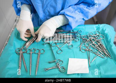 Mehrere Operationsinstrumente auf blauem Tisch über der Ansicht. Chirurg nehmen chirurgische Werkzeuge vom Tisch. Hochwertige Fotografie. Stockfoto