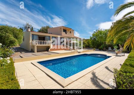 Moderne Villa mit Pool und tropischem Garten mit Palmen und Schaukelstuhl. Das Hotel ist eine Herberge für Touristen. Stockfoto