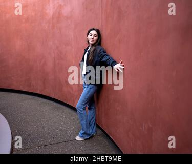 Teenager, die gegen eine rostfarbene Wand schiebt Stockfoto