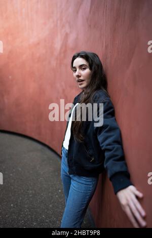 Teenager, die gegen eine rostfarbene Wand schiebt Stockfoto