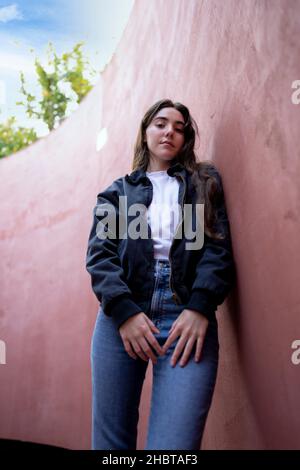 Junge Frau, die gegen eine rostfarbene Wand schiebt Stockfoto