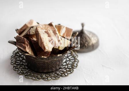 Teller mit Halva aus Sonnenblumenkernen auf einer Bronzeschale, selektiver Fokus. Stillleben mit Halva im arabischen Stil. Speicherplatz kopieren. Stockfoto