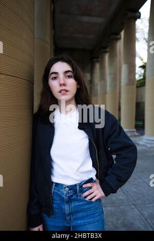 Teenagerin, die in einer Loggia gegen eine große Säule ansteht Stockfoto