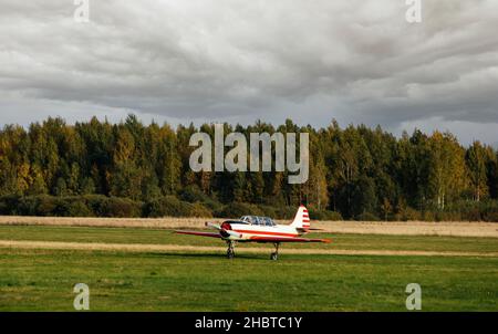 Sport Leichtmotorflugzeug auf dem Feld gegen den Himmel mit Wolken. Sportluftfahrt. Flugzeug Stockfoto