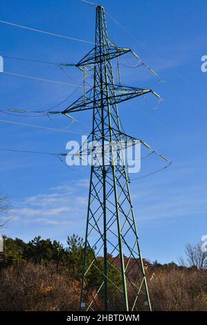 Übertragungsleitung. Elektrischer Getriebeturm. Übertragungsleitung wird gebaut.Hochspannungsturm mit Hintergrundbeleuchtung und idyllischem blauen Himmel. Stockfoto