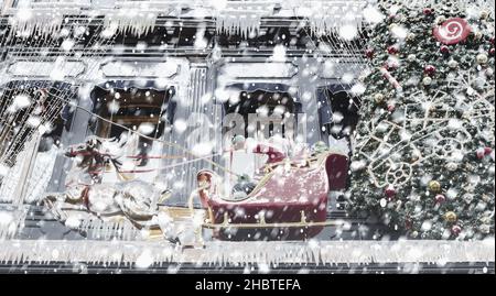 Ein Weihnachtsmann im Schlitten und ein Weihnachtsbaum, geschmückt mit bunten Kugeln und Schneeglöckchen Stockfoto