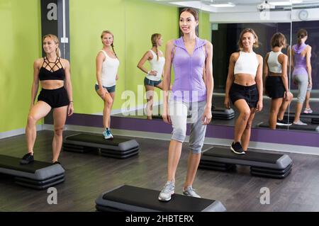 Lächelnde sportliche Frauen, die Step-Aerobic durchführen Stockfoto