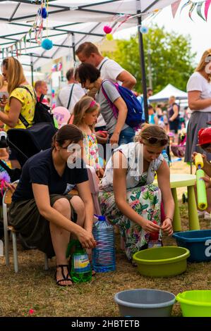 POZNAN, POLEN - 09. Jun 2018: Zwei junge Mütter bereiten bei einer Feuerwehrveranstaltung Wasser für Kinder vor, um mit Wasserpistolen zu spielen Stockfoto