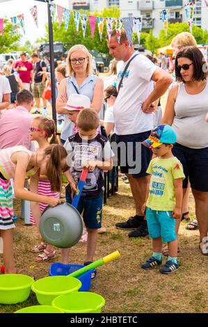 POZNAN, POLEN - 09. Jun 2018: Eine vertikale Aufnahme von Kindern, die bei einer Feuerwehrveranstaltung Wasser zum Spielen mit Wasserpistolen vorbereiten Stockfoto