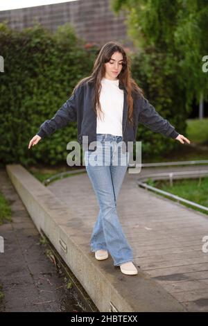 Teenager-Frau, die am Rande eines Gehwegs balanciert Stockfoto