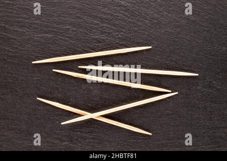 Mehrere Zahnstocher aus Holz auf einem Schieferstein, Nahaufnahme, Draufsicht. Stockfoto