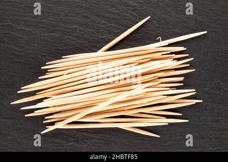 Mehrere Zahnstocher aus Holz auf einem Schieferstein, Nahaufnahme, Draufsicht. Stockfoto