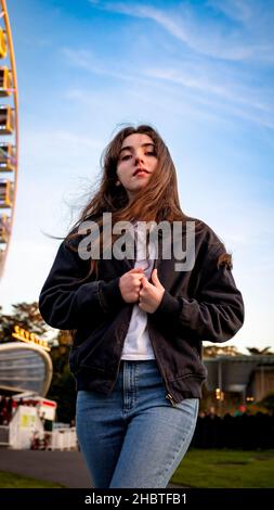 Junge Frau, die vor dem Riesenrad steht Stockfoto