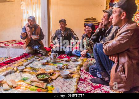 WAKHAN-TAL, TADSCHIKISTAN - 22. MAI 2018: Die Menschen vor Ort, die in einem Haus im Wakhan-Tal, Tadschikistan, Tee und Snacks genießen. Stockfoto