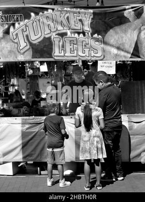 Ein Vater kauft geräucherte putenbeine für zwei Kinder von einem Lebensmittelhändler bei einem Outdoor-Festival in Santa Fe, New Mexico. Stockfoto