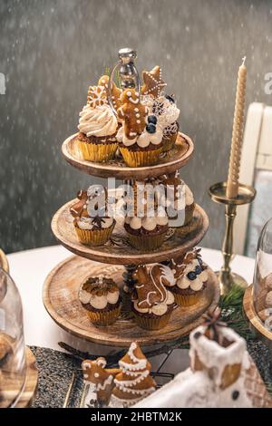 Köstliche Lebkuchen-Cupcakes mit Zimt und Weihnachtsgebäck und Schneeflockenstreuseln dekoriert Stockfoto