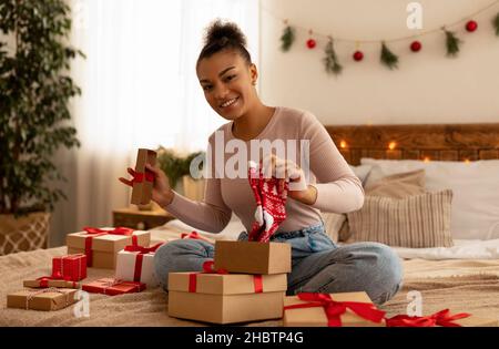 Neujahr und Weihnachtsfeier. Glückliche afroamerikanische Frau empfangen Weihnachtsgeschenk und hält niedliche Socken Stockfoto