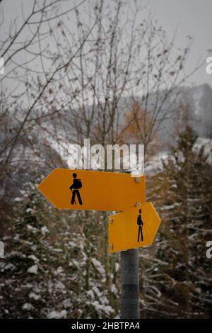 Gelbes Wanderzeichen auf verschneiten Bergen im Hintergrund Stockfoto