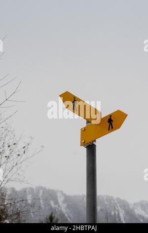 Gelbes Wanderzeichen auf verschneiten Bergen im Hintergrund Stockfoto