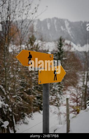 Gelbes Wanderzeichen auf verschneiten Bergen im Hintergrund Stockfoto