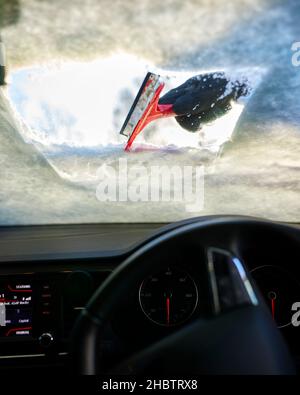 Fahrer räumt Schnee von der Windschutzscheibe Stockfoto