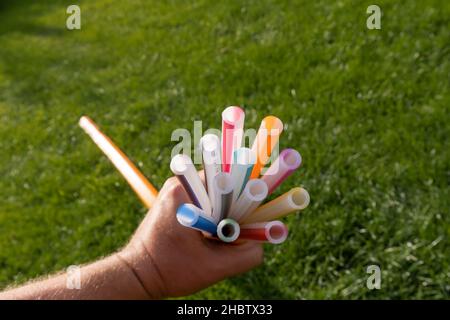 Hand mit leeren Röhren für Glasfaserkabel kommen auf einer Wiese aus dem Boden Stockfoto