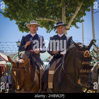 Sevilla, Provinz Sevilla, Andalusien, Südspanien. Feria de Abril, die Aprilmesse. Männliche Reiter halten für eine Sherry-Erfrischung während des Pferdes an Stockfoto
