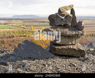 Eine Nahaufnahme von gestapelten Steinen mit Feldern im Hintergrund im Herbst an einem sonnigen Tag Stockfoto
