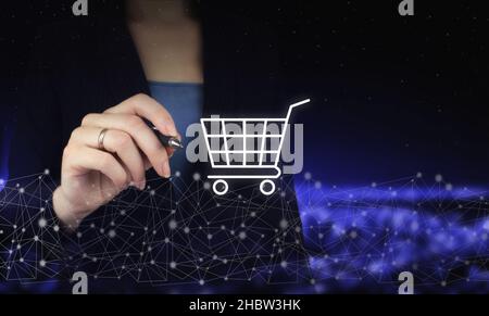 Online-Shopping Business Technologie Internet-Konzept. Hand hält digitale Grafik Stift und Zeichnung digitale Hologramm Wagen Zeichen auf Stadt dunkel verschwommen Bac Stockfoto