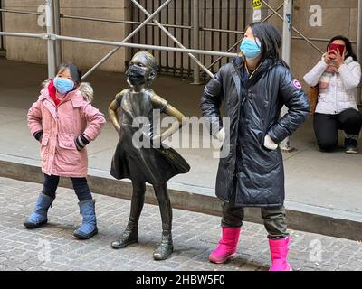 New York, Usa. 20th Dez 2021. Am 20. Dezember 2021 posieren zwei Personen an der Fearless Girl Statue vor dem New Yorker Börsengebäude in der Broad Street im Lower Manhattan. Fearless Girl ist eine Bronze Skulptur vier Meter hoch und wurde von der amerikanischen Bildhauerin Kristen Visbal entworfen. (Foto von Samuel Rigelhaupt/Sipa USA ) Quelle: SIPA USA/Alamy Live News Stockfoto