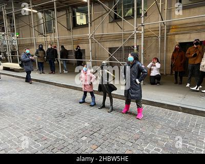 New York, Usa. 20th Dez 2021. Am 20. Dezember 2021 posieren zwei Personen an der Fearless Girl Statue vor dem New Yorker Börsengebäude in der Broad Street im Lower Manhattan. Fearless Girl ist eine Bronze Skulptur vier Meter hoch und wurde von der amerikanischen Bildhauerin Kristen Visbal entworfen. (Foto von Samuel Rigelhaupt/Sipa USA ) Quelle: SIPA USA/Alamy Live News Stockfoto