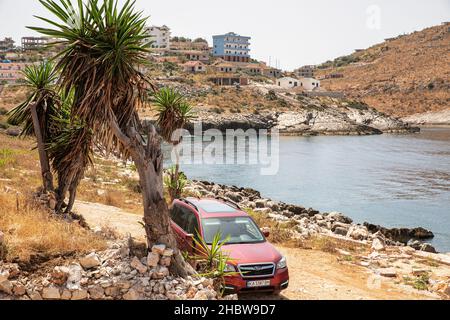 Saranda, Albanien - 29. Juli 2021: Cherry Subaru Forester parkte an einem felsigen Strand. Saranda liegt an einem offenen MeeresGolf des Ionischen Meeres innerhalb der Stockfoto