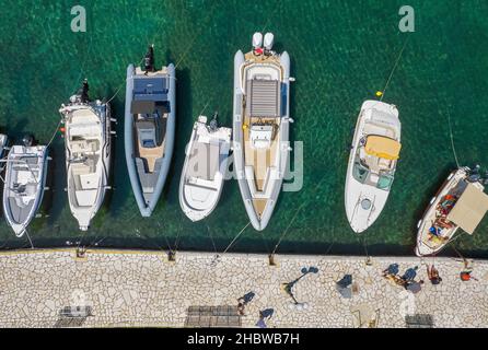 KASSIOPI, KORFU, GRIECHENLAND - 7. AUGUST 2021: Luftdrohnenansicht über moderne Motorboote, die im Alten Hafen festgemacht sind. Kassiopi war historisch eine kleine Tradition Stockfoto