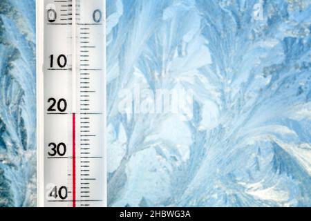 Das Thermometer zeigt eine niedrige Temperatur von minus 20 Celsius an. Wettervorhersage. Ein frostiger Tag und Eismuster auf dem Glas Stockfoto