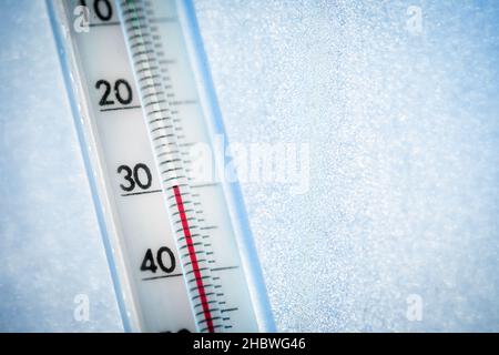 Das Thermometer zeigt eine niedrige Temperatur von minus 30 Celsius an. Wettervorhersage. Ein frostiger Tag und Eismuster auf dem Glas Stockfoto