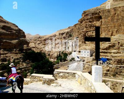 Ein kleines Mädchen, das auf einem Esel in Richtung Kloster des heiligen Georg von Choziba reitet, Wadi Qelt Stockfoto