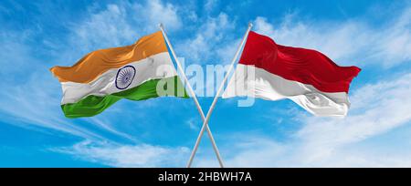 Gekreuzte Nationalflaggen Indiens und die Flagge von Monaco winken im Wind bei bewölktem Himmel. Symbolisiert Beziehung, Dialog, Reisen zwischen zwei Ländern. Stockfoto
