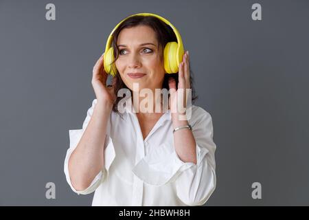 Schöne Frau, die über kabellose Kopfhörer Musik hört Stockfoto