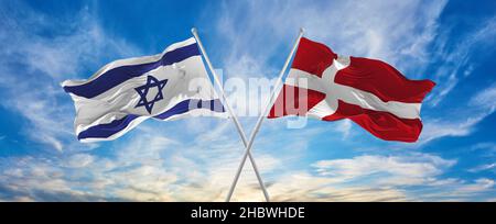 Gekreuzte Nationalflaggen von Israel und dänemark, die im Wind bei bewölktem Himmel winken. Symbolisiert Beziehung, Dialog, Reisen zwischen zwei Ländern Stockfoto