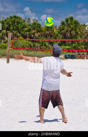 Ein hispanischer Mann in den 60ern, der Volleyball an einem Strand spielt Stockfoto