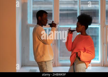 Das junge afrikanische Paar genießt einen romantischen Abend mit Wein zu Hause, der schwarze Mann und die schwarze Frau bei einem Date Night Stockfoto