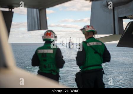 211220-N-PG226-1046 MEDITTERANIAN SEA (DEZ 20, 2021) der Lenkflugzeugkreuzer USS San Jacinto (CG 56) der Ticonderoga-Klasse und die Royal Norwegian Navy Frigate HNoMS Fridtjof Nansen (F310) fahren hinter dem Flugzeugträger USS Harry S. Truman (CVN 75) der Nimitz-Klasse, 20. Dezember 2021. Die Harry S. Truman Carrier Strike Group ist im Rahmen eines geplanten Einsatzgebiets der Sechsten Flotte der USA zur Unterstützung von Marineoperationen im Hinblick auf die Aufrechterhaltung der Stabilität und Sicherheit im Seeverkehr sowie die Verteidigung der Interessen der USA, der Alliierten und Partner in Europa und Afrika im Einsatz. (USA Navy Foto von Mass Communication Specialist 3rd Class Stockfoto