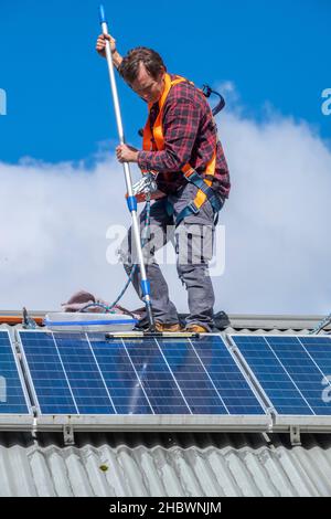 Handwerker, der Solarpaneele auf dem Dach des Hauses reinigt Stockfoto