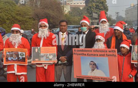 Lahore, Pakistan. 21st Dez 2021. Pakistanische Aktivisten der Bright Future Society und der IMRF tragen die Kostüme des Weihnachtsmannes, halten Plakate und zünden Kerzen an während der Demonstration an, um Solidarität mit der Familie der srilankischen Managerin Priyantha Kumara vor dem Presseclub in Lahore zu zeigen. Quelle: Pacific Press Media Production Corp./Alamy Live News Stockfoto