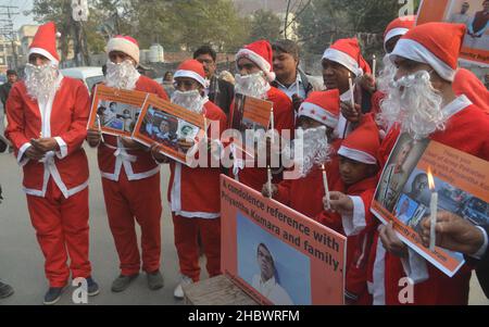 Lahore, Pakistan. 21st Dez 2021. Pakistanische Aktivisten der Bright Future Society und der IMRF tragen die Kostüme des Weihnachtsmannes, halten Plakate und zünden Kerzen an während der Demonstration an, um Solidarität mit der Familie der srilankischen Managerin Priyantha Kumara vor dem Presseclub in Lahore zu zeigen. Quelle: Pacific Press Media Production Corp./Alamy Live News Stockfoto
