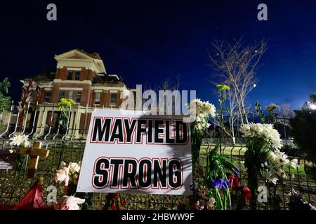 MAYFIELD, KENTUCKY - 20. DEZEMBER: Ein Schild mit der Aufschrift „Mayfield Strong, links, wo Blumen und Fotos von Verstorbenen am 20. Dezember 2021 in Mayfield, Kentucky, ein provisorisches Denkmal auf einem Zaun um das Graves County Gerichtsgebäude herum errichten. Mehrere nächtliche Tornados schlugen am 10. Dezember in mehreren Bundesstaaten des Mittleren Westens ein, was zu weit verbreiteten Zerstörungen und mehreren Verletzten führte. Stockfoto