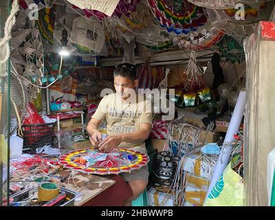 27. November 2021, Philippinen, Elias Aldana: Andrew Flores, 48, fügt einer Bewährung aus Capiz-Muscheln in seinem kleinen Weihnachtsdekor-Laden im Dorf Elias Aldana in Las Pinas City in Metro Manila Glühbirnen hinzu. Im südostasiatischen Inselstaat werden bereits im Mai riesige Mengen sternförmiger Laternen hergestellt. Die Weihnachtsschmuck werden als "Parolen" bezeichnet, und sie existieren nur auf den katholischen Philippinen. Sie werden traditionell aus Bambusstäben und buntem japanischem Papier hergestellt. Heute werden aber auch andere Materialien wie Metalldrähte, Fiberglas und Kunststofffolien verwendet. Foto: Dhang De Stockfoto