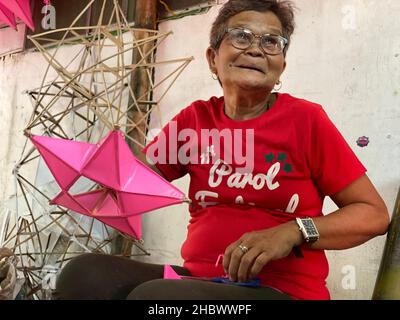 Elias Aldana, Philippinen. 27th. November 2021. Alicia Bencio, eine 65-jährige Malerin aus dem Dorf Elias Aldana in Las Pinas City in Metro Manila, macht in ihrem Hinterhof Parolen. Bencio und ihre Familie verwenden Bambusstäbchen und Plastikfolien, um die traditionellen fünfzackigen Sternlaternen zu machen. (To dpa: 'Seltsame Dinge für die Feiertage: Von tanzenden Teufeln und Karpfen in der Wanne') Quelle: Dhang De Castro/dpa/Alamy Live News Stockfoto