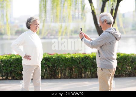 Älterer Mann, der mit seinem Mobiltelefon Fotos von seiner Frau machte Stockfoto